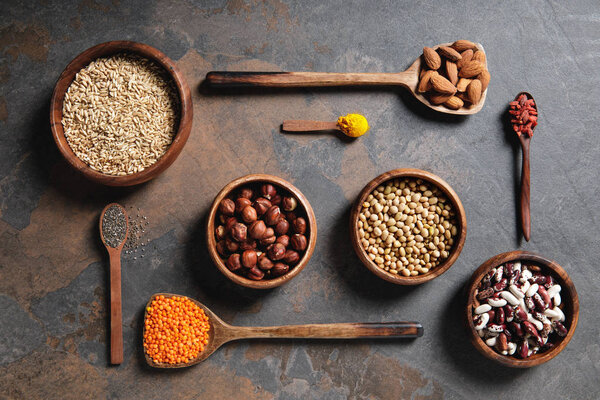 top view of wooden bowls and spoons with superfoods, legumes and grains on table