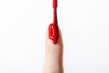 cropped view of woman applying dripping red nail polish on fingernail isolated on grey clipart