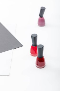 top view of three bottles of red, burgundy and pink nail polish on white clipart