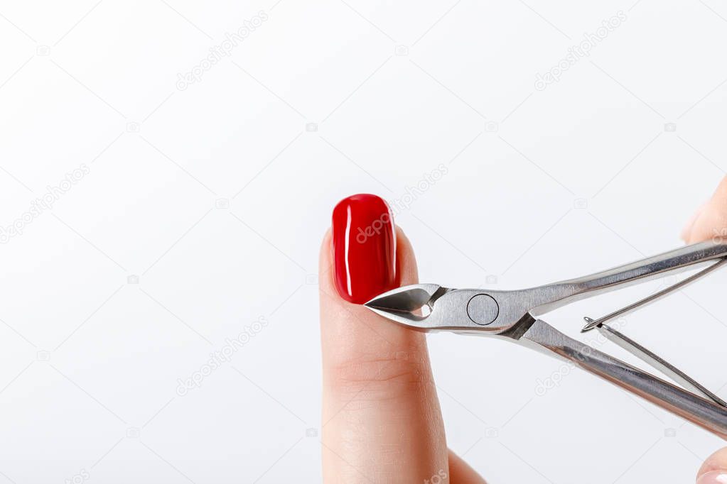 manicurist using cuticle nipper on fingernail with red nail polish isolated on white