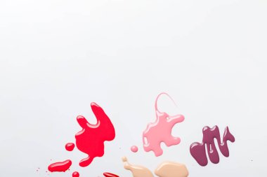 top view of wet multicolored spills of nail polish isolated on grey clipart