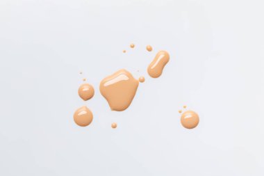 top view of wet and shiny caramel drops of nail polish isolated on grey clipart