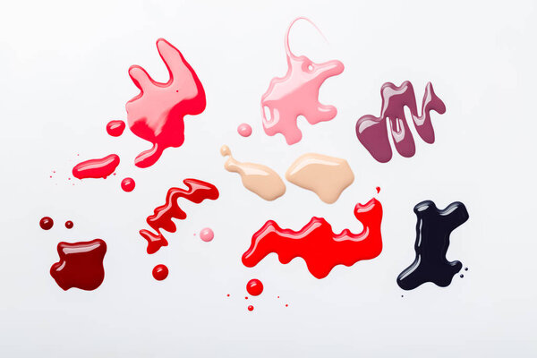 top view of abstract spills of nail polish with drops isolated on grey