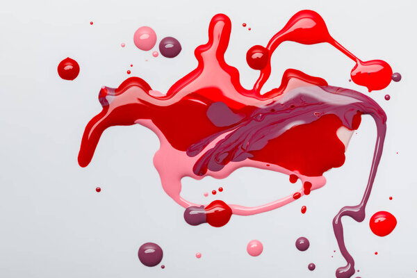 вид сверху абстрактный и красочный пролитый лак для ногтей изолирован на сером
 