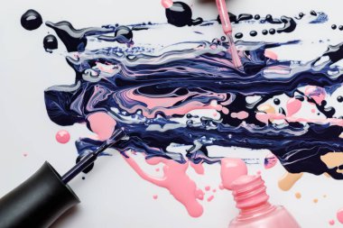 top view of abstract multicolored spill of nail polish with wet brushes isolated on grey clipart