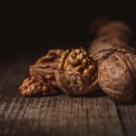 Close up view of shelled and whole walnuts on wooden tabletop