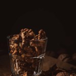 Close up view of shelled walnuts in glass on black backdrop