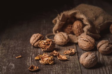close up view of walnuts in sack on wooden background clipart