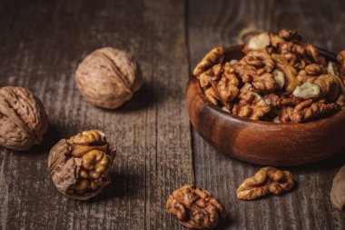 close up view of walnuts in bowl on wooden surface clipart
