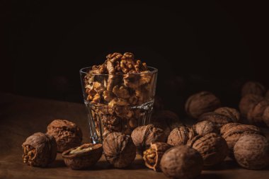 close up view of shelled walnuts in glass on black backdrop clipart