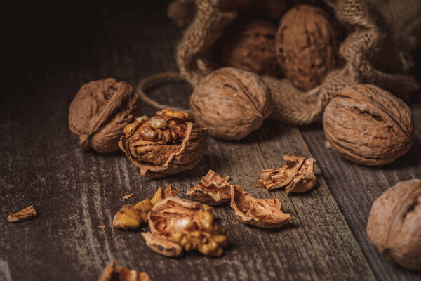 close up view of walnuts in sack on wooden background