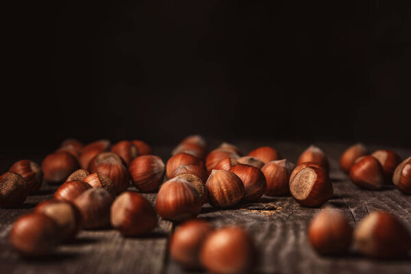 close up view of hazelnuts on wooden surface on black background