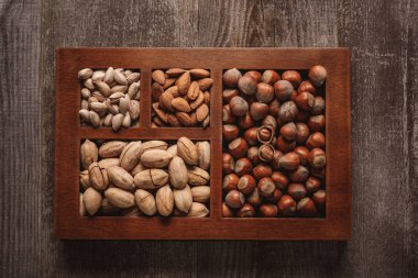 top view of assortment of various nuts in box on wooden background clipart
