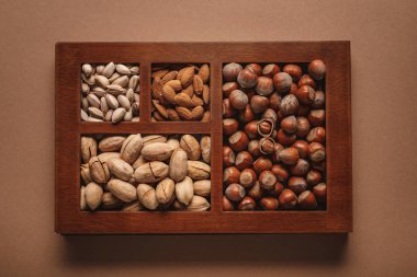 top view of assortment of various nuts in box on brown background clipart