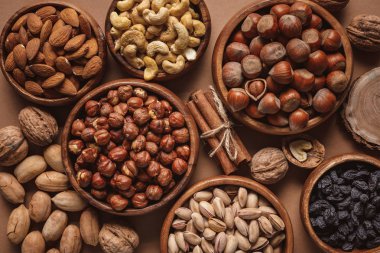 flat lay with variety of nuts in bowls arranged on brown background clipart