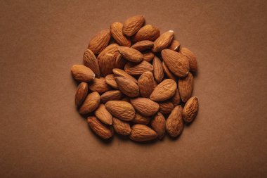 top view of pile of almonds on brown backdrop clipart