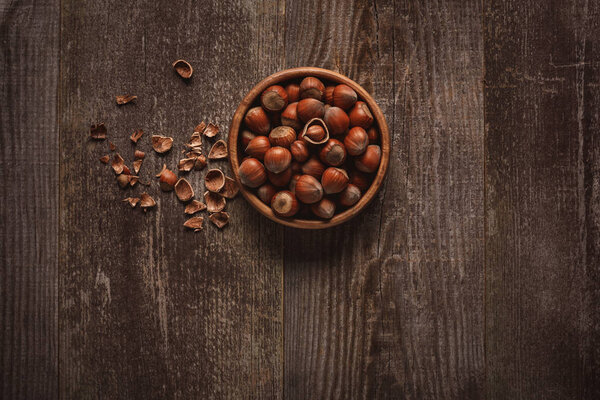 top view of hazelnuts in bowl on wooden tabletop 