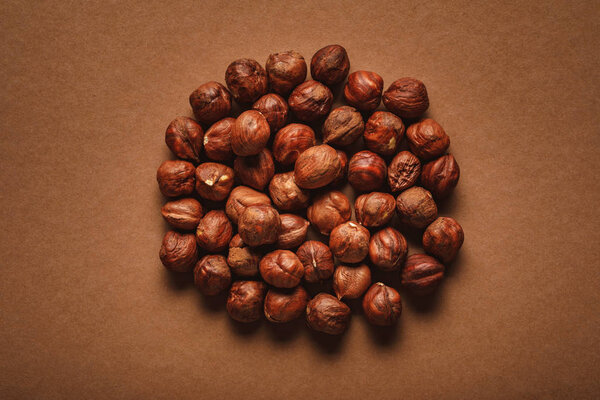 top view of pile of shelled hazelnuts on brown backdrop