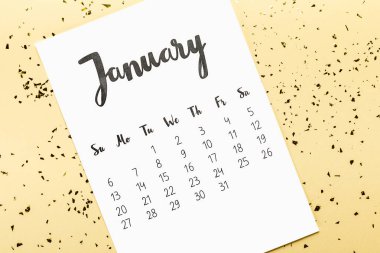 top view of january calendar and golden confetti on beige clipart