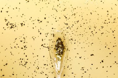 şampanya kadehi ve bej renkli arka plan üzerinde şenlikli altın konfeti  