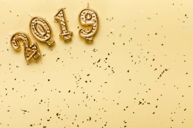 bej renkli arka plan üzerinde 2019 mumlar ve altın konfeti üstten görünüm