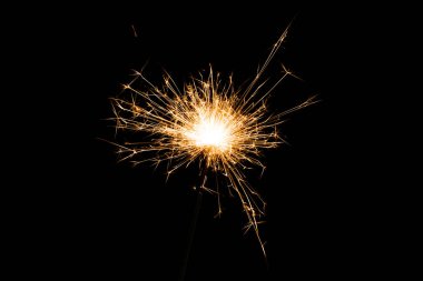 close-up view of burning and glowing christmas sparkler on black background clipart