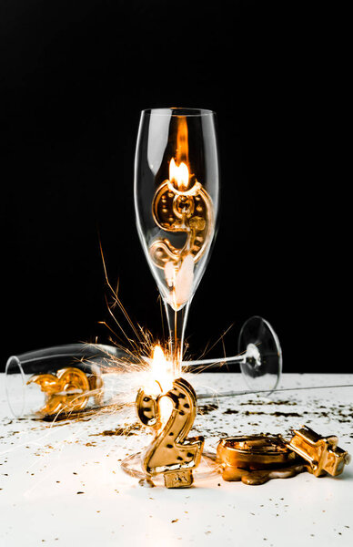 close-up view of glasses, sparkler and golden 2019 numbers on black  