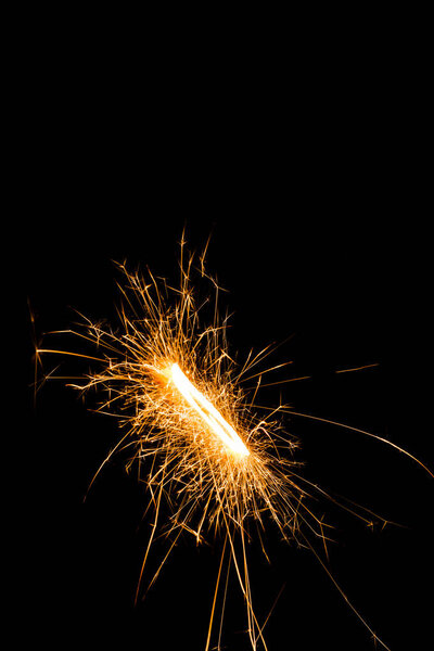 close-up view of glowing new year sparkler on black background 