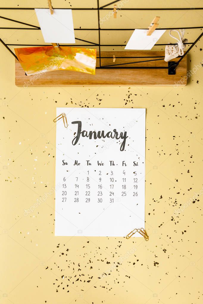 top view of january calendar with golden confetti and cards with clothespins on beige