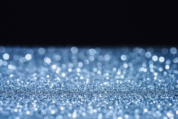 selective focus of blurred sparkling surface on black
