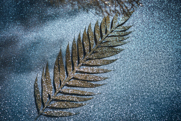 селективный фокус праздничной ветви, украшенной золотым блеском на блестящей поверхности
