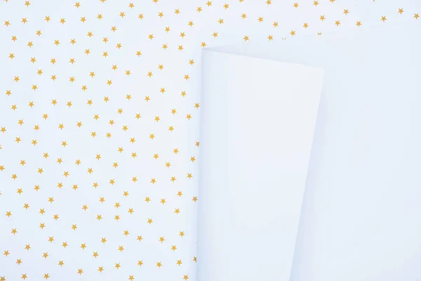 elevated view of white empty paper on festive surface decorated by golden stars 