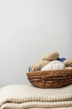close up view of yarn clews in wicker basket on grey backdrop clipart