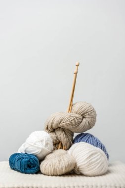 close up view of knitting clews with knitting needles on grey backdrop clipart