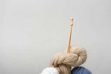 close up view of knitting clews with knitting needles on grey backdrop clipart