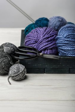 beyaz masa üzerinde iplik topları ve makas ahşap kutusunda görünümü kadar kapatın