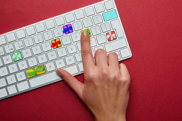 赤の背景 オンラインのクリスマス ショッピングのコンセプトにギフト ボックスとコンピューターのキーボードを持つ女性のビューをトリミング — ストック写真