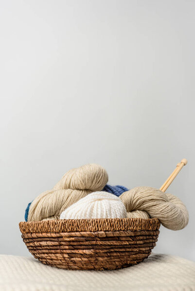 close up view of yarn cleans in wicker basket on grey backdrop
