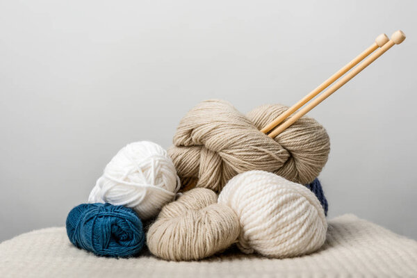 close up view of knitting needles in yarn clews on grey background