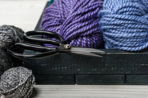 Закрыть вид пряжи шары и ножницы в деревянной коробке на белой столешнице
