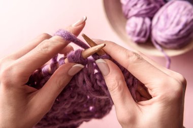 partial view of woman knitting yarn on pink background clipart