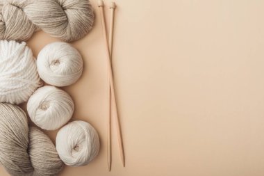 flat lay with yarn and knitting needles on beige backdrop clipart