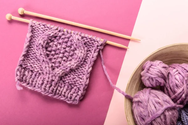 平躺在粉红色和紫色背景下 用紫色纱线在碗里包 用针织针织 — 图库照片