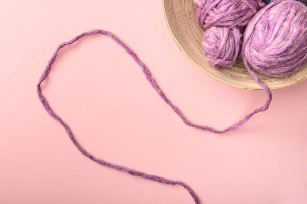 top view of purple knitting in bowl on pink tabletop