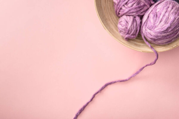 top view of purple knitting in bowl on pink tabletop