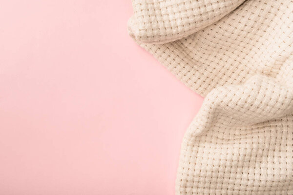 top view of white knitted blanket on pink background