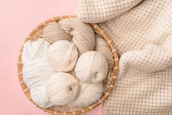 Top view of yarn in wicker basket on pink background with knitted blanket — Stock Image Top View Yarn Wicker Basket Pink Background Knitted Blanket Stock Picture