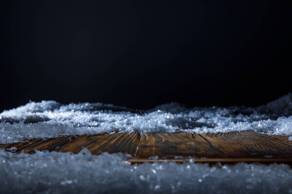 brown wooden board covered with snow on black