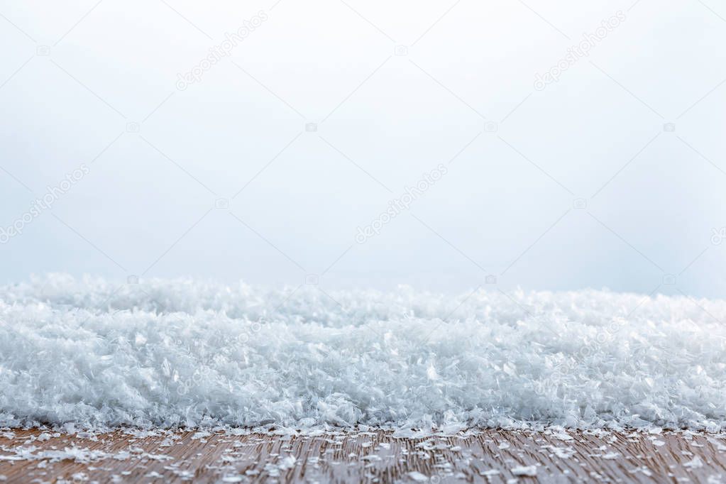 close up of striped wooden board covered with snow on white