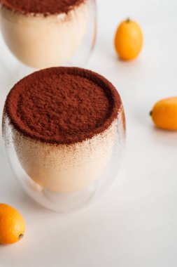 tiramisu desserts with cocoa powder and kumquats in two glasses clipart